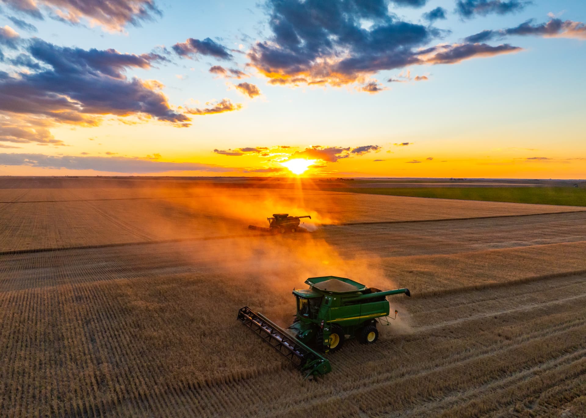 Combine harvesters working a wheat field at sunset in the Nebraska Panhandle